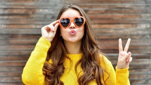 Vertical portrait of blond female in red smart casual dress posing near banana palm tree with big leaves