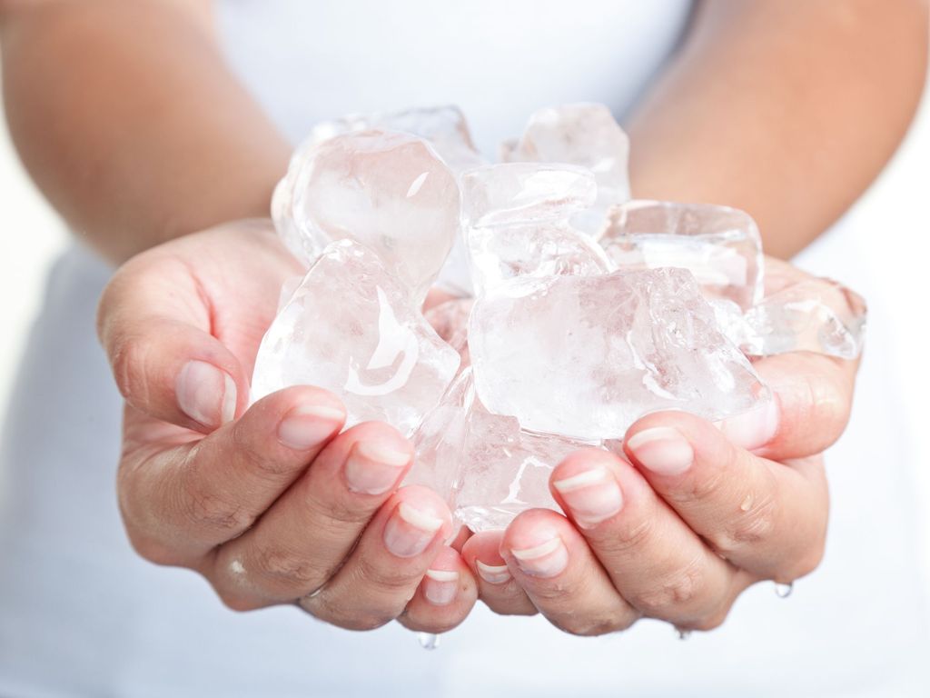 cropped view of seductive woman holding ice cube in mouth, isolated on white