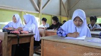 Para siswa tetap semangat meski harus belajar di ruangan kelas yang rusak parah.