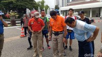 Sandiaga memakai polo shirt warna oranye dengan lambang satpol PP serta celana cokelat dan sepatu khusus.