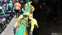 Yang satu mengecat, petugas lainnya memegangi tangan temennya.