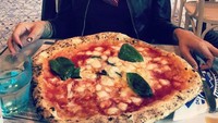 Bertandang ke Italia, Niki tak melewatkan pizza lezatnya. Seloyang pizza Italia sudah ada dihadapannya. Dengan wajah tak sabar melahap, Niki terlihat fokus memandangi pizza. Foto: Instagram @nikitamirzanimawardi_17