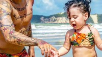 Pose Firmino saat mengajak buah hatinya Valentina Firmino, liburan ke pantai (@roberto_firmino/Instagram)
