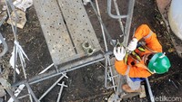 Seorang pekerja tengah merakit scaffolding.