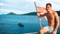Foto: Stoffel berpose di kapal sambil bertelanjang dada. Sambil memegang bendera Indonesia, dia mengagumi keindahan laut Raja Ampat. (Instagram/@svandoorne)