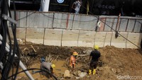 Bus TransJakarta melintas di samping para pekerja yang tengah membangun rangka tiang LRT.