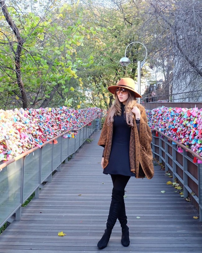 Gaya Astrid Ellena dengan sentuhan bohemian. Ia memadukan cape dengan topi berwarna senada di bawah dress dan legging berpalet gelap agar tampil lebih fashionable. Foto: Instagram