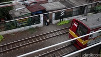 Seorang warga menunggu kereta melintas untuk menyebrang di rel.