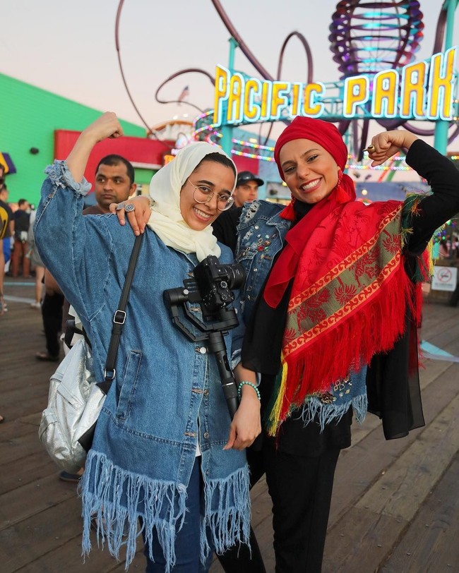 Saat mengunjungi Santa Monica di LA, California, Haida Basseiso mengenakan rompi jeans, anting tassel dipadukan dengan pashmina merah. Foto: Instagram