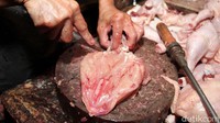 Pedagang memotong daging ayam pesanan pembeli.