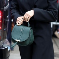 Tidak ketinggalan tas De Mellier London yang dipermanis dengan aksen fringe. Warna hijau zamrudnya seolah menghidupkan gaya busananya yang bernuansa gelap. (Foto: Getty Images)