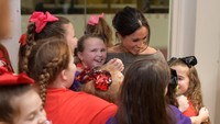 Meghan tampak tersenyum saat mendapat sambutan hangat dari anak-anak perempuan ini