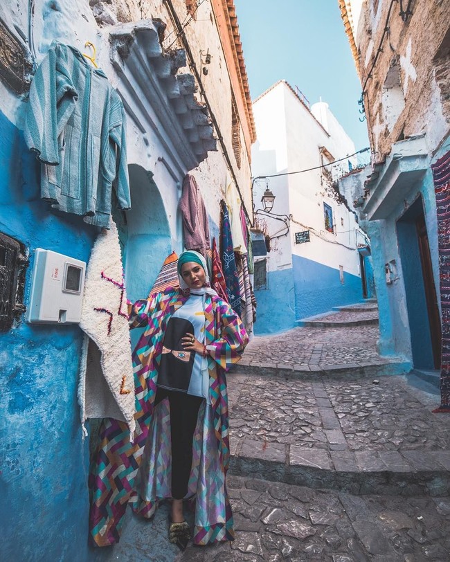 Saat mengunjungi Maroko, Haifa Basseiso mengenakan outerwear dengan corak geometris dan kaos bergambar wanita berniqab. Warnanya senada dengan bangunan di sana, so stylish! Foto: Instagram