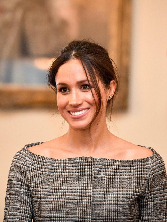 Berada di dalam ruangan, Meghan Markle membuka mantel tersebut dan terungkaplah blus abu-abu bermotif kotak-kotak sebagai atasan. Garis leher model bateau neck atau sabrina mengekspos bahu Meghan yang indah. (Foto: Getty Images)