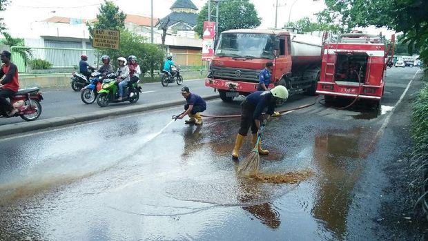 Petugas PMK berusaha membersihkan tetes di jalan dengan semprotan air