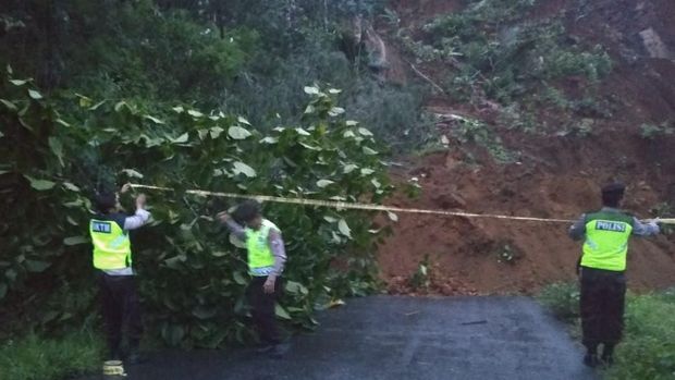 Polisi memasang police line di jalan yang tertimbun longsor