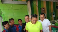 Sandi tampak mengenakan kaos warna hijau dengan celana sport pendek (Foto: Eva Safitri/detikcom)
