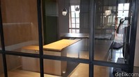Ia menunjukkan sebuah ruangan kecil yang bertembok kaca, ada dua set meja kayu di situ yang bersebelahan.