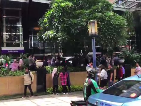 Para pekerja keluar dari gedung dan berkumpul di tempat aman saat merasakan gempa