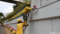 Pekerja harus memanjat tangga untuk menjangkau dinding bagian atas.