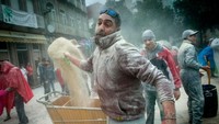 Para penduduk berkumpul di pusat kota dan saling berperang lempar tepung. (AFP)
