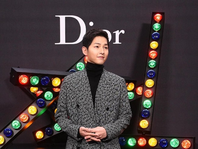 Berpose di backdrop Dior, senyuman manis aktor 32 tahun itu selalu mengembang di bibirnya.  Foto: dok. Getty Images