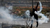 Seorang demostran melemparkan kembali gas air mata yang ditembakkan polisi Israel. REUTERS/Mohamad Torokman.