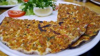 Inilah dia Lahmacun, pizzanya Turki. Lahmacun bentuknya lingkaran yang dibelah dua, disajikan di atas piring putih bersama selada, tomat hingga lemon (Kurnia/detikTravel)
