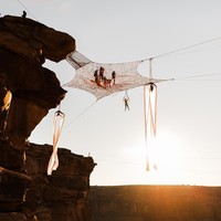 Selama upacara pernikahan berlangsung, teman-temannya melakukan aksi di bawah jaring, beberapa melakukan akro-yoga di tepian tebing, beberapa yang lainnya terbang di atas paralayang, dan memainkan seruling. Foto: Instagram @_kimw_