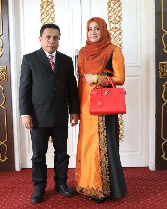 Darwati, istri Gubernur Aceh Irwandi Yusuf, bergaya penuh warna dengan busana muslim oranye-hitam dan tas Louis Vuitton seri Twist Tote berwarna merah seharga US$ 3.000 atau sekitar Rp 39 juta. (Foto: dok. Instagram)