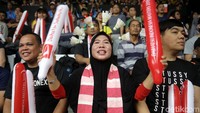 Seorang suporter menghias bando menggunakan shuttlecock.