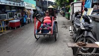 Tukang becak mengantar penumpang.