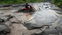Pengendara ini nampak nekat menerobos aliran lahar dingin di sungai dengan sepeda motornya. Foto: REUTERS/Romeo Ranoco