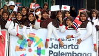 Puluhan pelajar mengibarkan bendera dari berbagai negara peserta Tour de Indonesia 2018 di belakang spanduk bertuliskan Asian Games Jakarta-Palembang 2018.