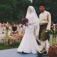 Saat akad nikah, Yuna Zarai mengenakan turban ditambah veil yang menutupi kepala hingga dadanya. Turban yang ia kenakan ditambah dengan aksen bunga di bagian belakang. Yuna Zarai memilih desainer Hattal Dolmat untuk hari spesialnya itu. Hattal Dolmat berteman dekat dengan Yuna, mereka juga pernah membuat koleksi kolaborasi. Foto: Instagram