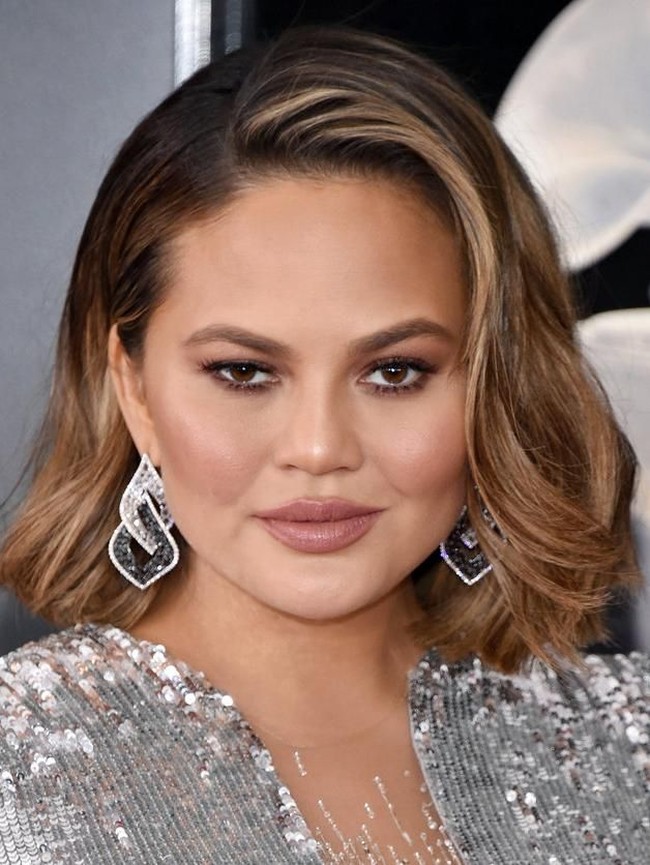 Mengikuti tren rambut 2018, Chrissy Teigen tampil dengan rambut lob (long bob). Sementara makeupnya bernuansa bronzy yang memberikan efek glowy skin.  Foto: Getty Images
