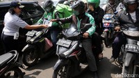 Petugas Dinas Perhubungan DKI Jakarta membagikan pamflet sosialisasi kepada pengendara sepeda motor.
