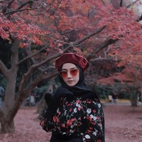 Menikmati dedaunan yang jatuh di musim gugur, Nisa Cookie tampil matching dengan busana motif floral berwarna hitam dan merah. Ia pun memakai topi baret dan kaca mata berwarna senada. Foto: Instagram