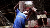 Seorang pekerja menuangkan cairan ke dalam cetakan lilin.