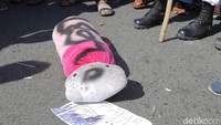 Boneka Hello Kitty warna pink dan kepala putih itu diletakkan di atas jalan dan dikerumuni massa.