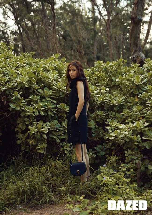 Imutnya Min Hyo Rin berbalut shift dress hitam dengan latar belakang tanaman hijau. Foto: dok. Dazed