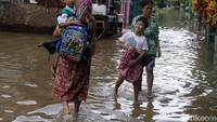 Seorang anak yang disunat melewati genangan air di Cipinang Melayu, Jakarta Timur, Senin (5/2/2018).