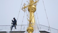 Seorang pria membersihkan salju di atas sebuah gedung di dekat gereja di pusat Kota Moskow (Foto: Dok. REUTERS/Sergei Karpukhin)