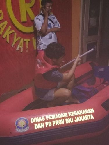 Petugas mengevakuasi warga menggunakan perahu karet