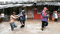 Lela dievakuasi petugas dengan cara digendong. Tampak wanita tersebut dipakaikan jas hujan.
