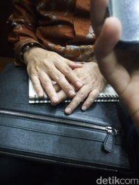 Tangan Novanto menutup buku catatan yang dikeluarkan di pengadilan.