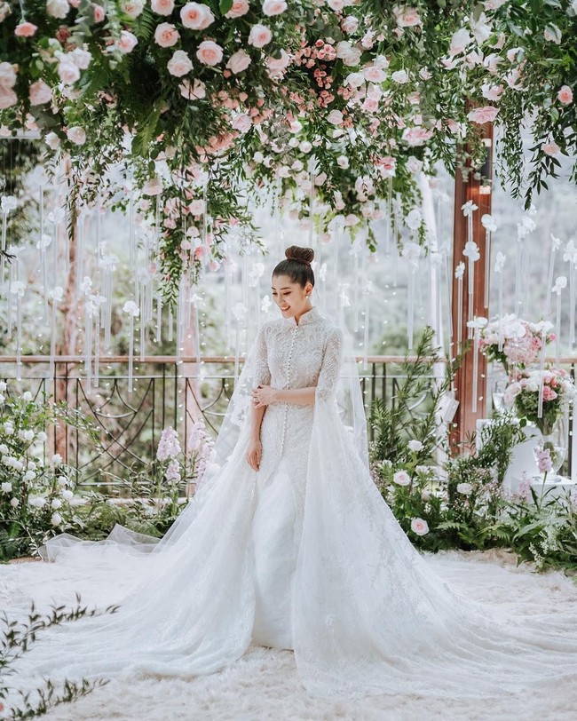 Dalam pernikahannya, Chryseis Tan memakai gaun pengantin rancangan desainer Indonesia, Yefta Gunawan. Gaun pengantin berwarna putih itu terlihat dihiasi cape dan ekor yang sangat panjang sehingga menambah kesan elegan dan mewah. Foto: Dok. Instagram Ivan Mario (Axioo), YSA Events, Chryseis Tan
