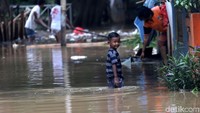 Seorang anak bermain di genangan.
