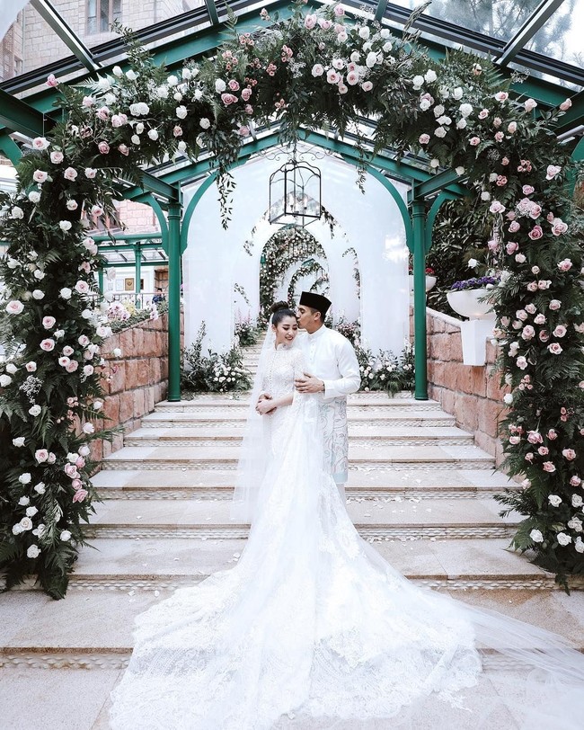 Pernikahan Chryseis Tan dan Faliq Nasimuddin digelar dengan elegan dan mewah. Dekorasi penuh bunga menghiasi area pelaminan. Tampak area The Chateau dihiasi beberapa arch atau gapura yang dipenuhi bunga mawar pink dan putih. Foto: Dok. Instagram Ivan Mario (Axioo), YSA Events, Chryseis Tan