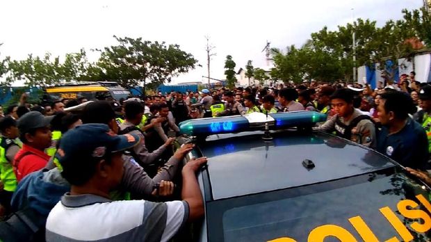 Konsumen menghadang mobil polisi yang membawa orang yang menodongkan pistol 